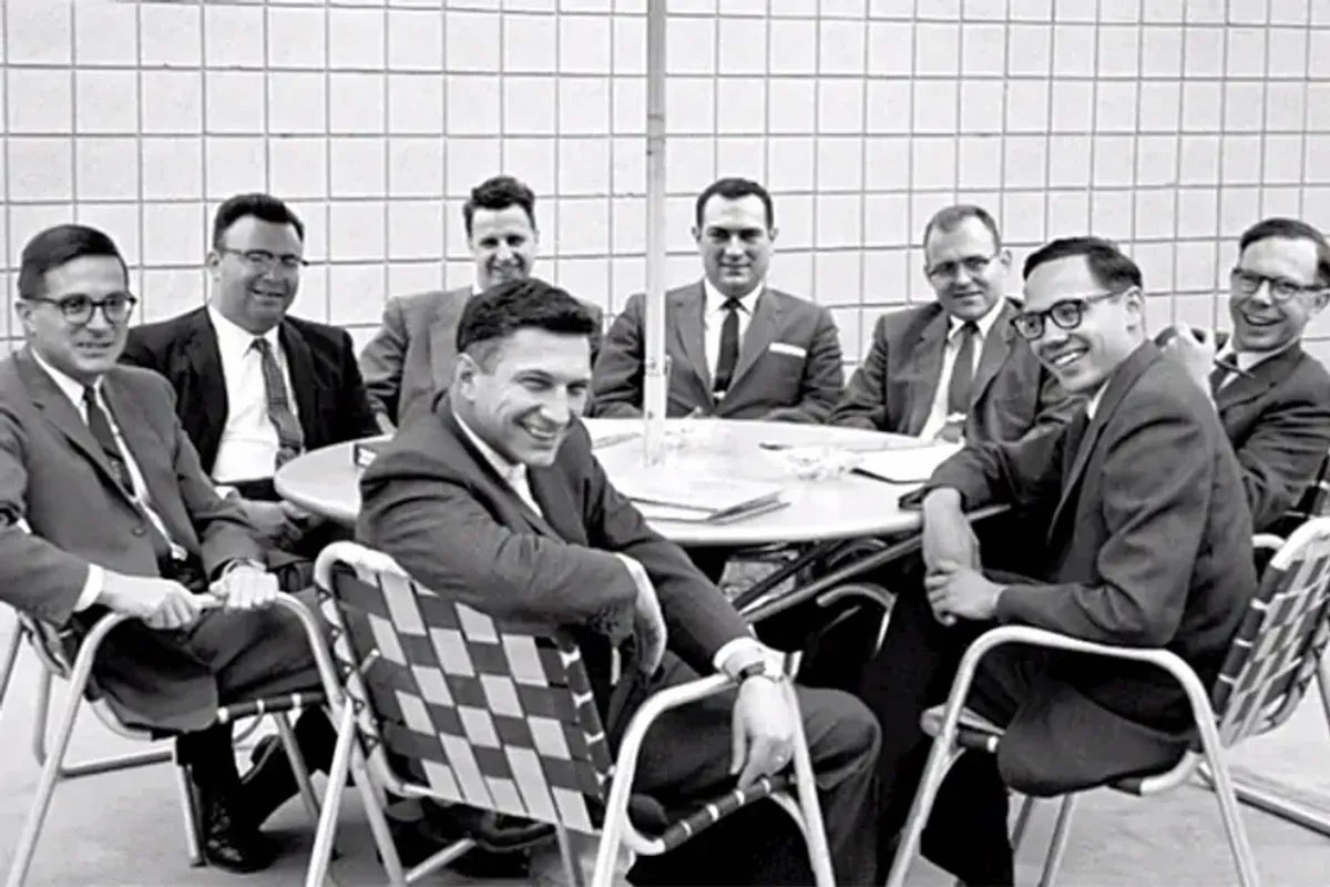 The Traitorous Eight gathered around a table, smiling, after founding Fairchild Semiconductor